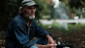 A person sitting in a serene park, holding a flower instead of a cigarette.