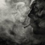 Photograph: Moody portrait of a person surrounded by cigarette smoke, reflecting unstable mood.