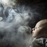 Infant surrounded by cigarette smoke, highlighting health risks - high-resolution photograph